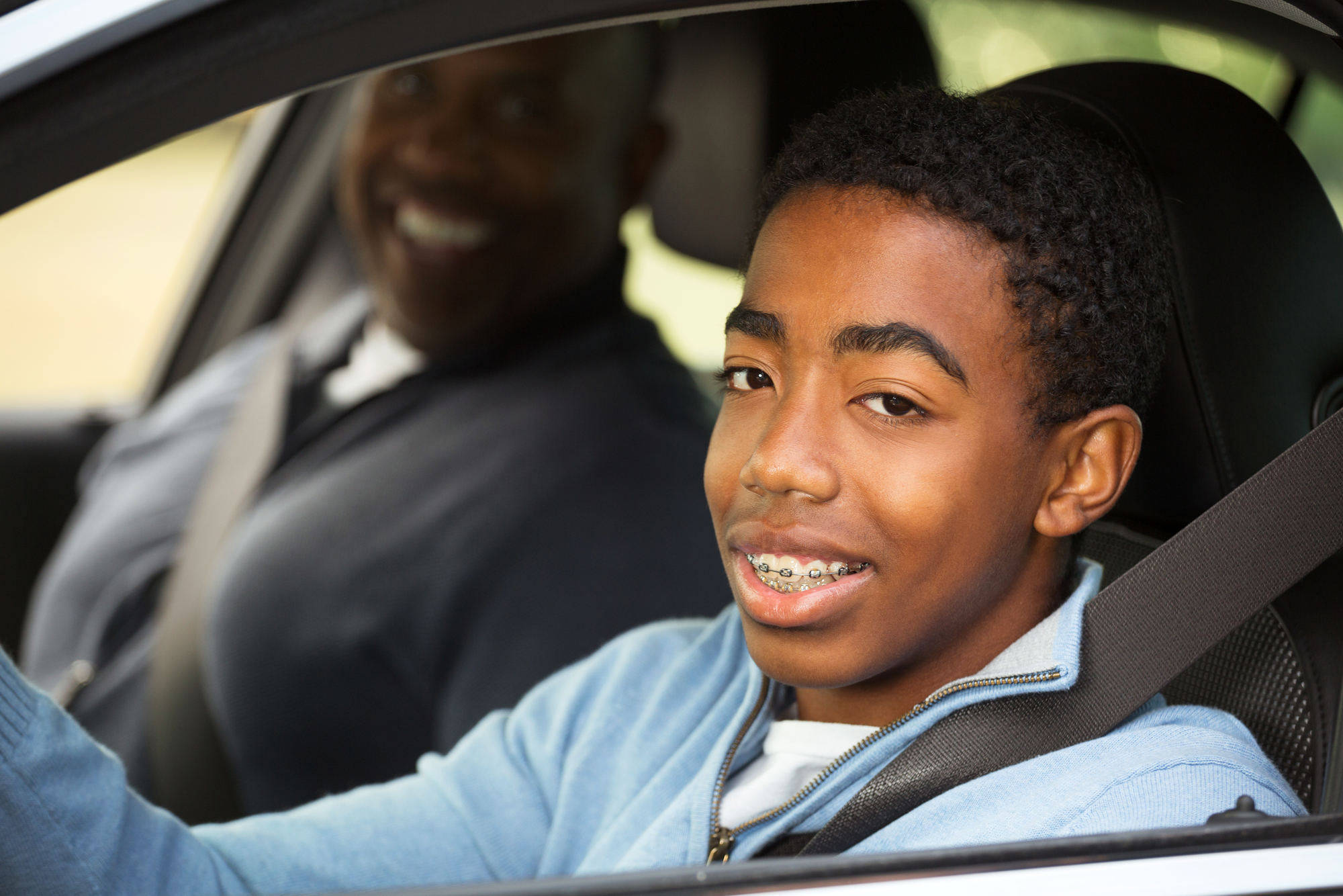 Young man driving a car with an instructor